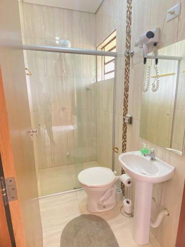 a bathroom with a shower and a toilet and a sink at Pousada Bela Vista in Sengés