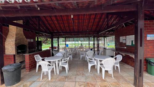 a patio with tables and chairs and a fireplace at Chalé Lazer Gravatá com 3 suítes - na Suíça Brasileira in Gravatá