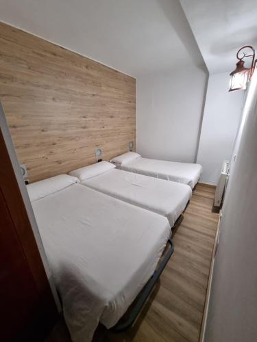 two beds in a small room with a wooden wall at Hotel Avanti in Pas de la Casa