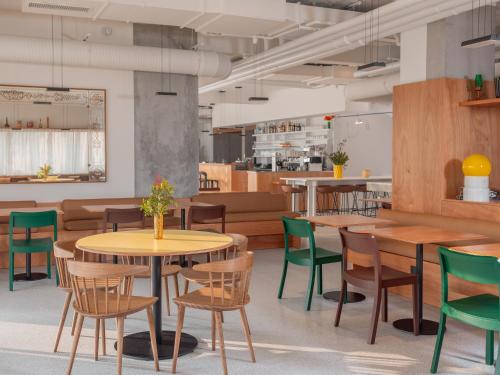 a restaurant with wooden tables and green chairs at Hôtel Vertime in Les Sables-dʼOlonne