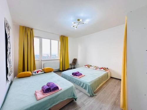 two beds in a room with yellow curtains at Гавань Счастья in Almaty