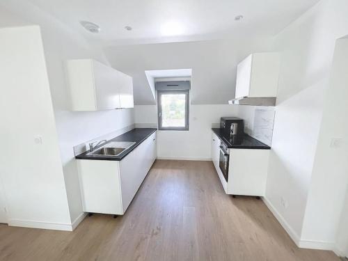 une cuisine avec des armoires blanches et un plancher en bois dans l'établissement Appartement neuf proche gare, à Margny-lès-Compiègne