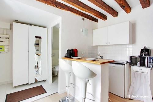 une cuisine avec des armoires blanches et un comptoir dans l'établissement Cozy studio 2P - Rue Mouffetard, à Paris