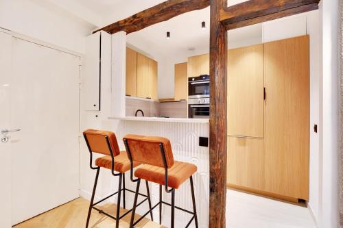 - une cuisine avec deux tabourets de bar et des placards en bois dans l'établissement Saint-Honore - Sublime appartement 3 personnes, à Paris