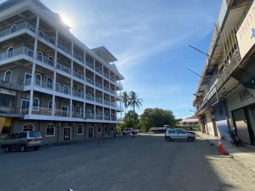 a large building with cars parked in front of it at GLhotel kudat in Kudat