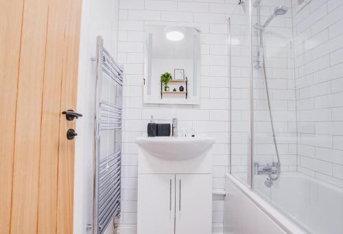 Un baño blanco con lavabo y bañera. en Luxury 2 Bed in Reading - Free Parking & Fast Wi-Fi, en Reading