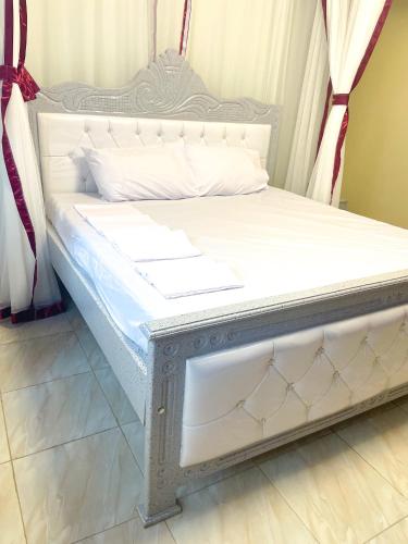 a bed with a white bed frame in a room at Cozy Residence III 2bedroom Apartment near Speke Resort in Kampala