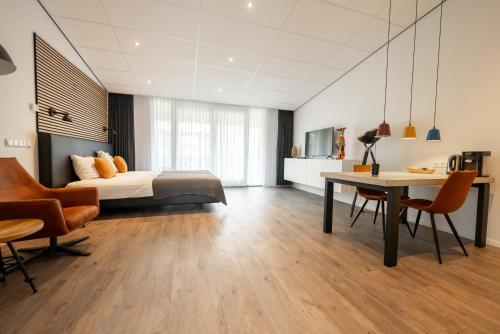 a bedroom with a bed and a desk and chairs at De Berkenhof Aparthotel in Nes