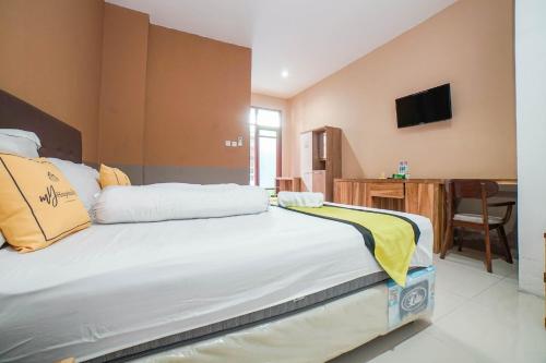 a bedroom with a large bed with a tv on the wall at Blok O International Guest House by MHM in Demangan