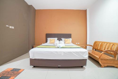 a bedroom with a bed and a wooden bench at Blok O International Guest House by MHM in Demangan