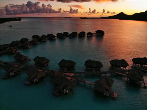a group of huts in the water at sunset at InterContinental Bora Bora & Thalasso Spa by IHG in Bora Bora