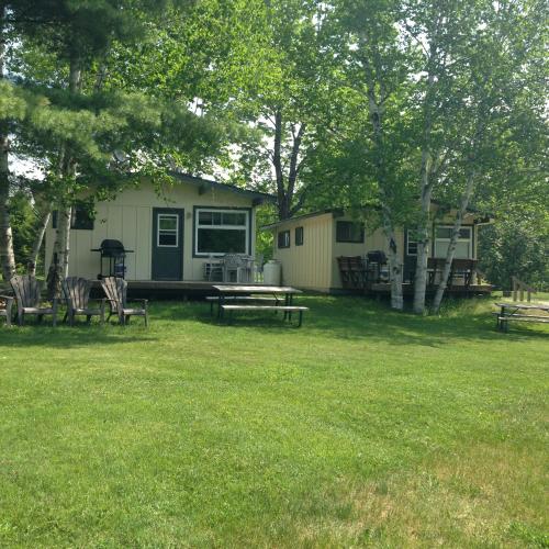 a house with a picnic table and chairs in a yard at Colonial Bay Motel and Cottages in Huntsville