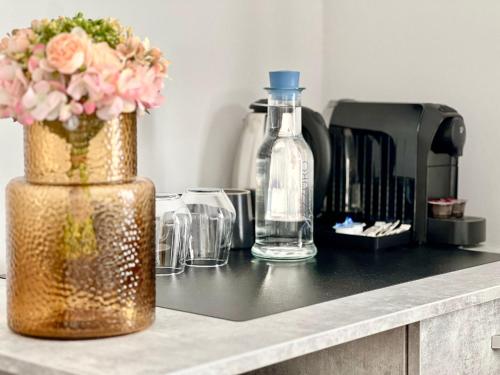 a counter top with a vase of flowers and glasses at Hotel Fantazia Oradea - Self Check In & Out in Oradea