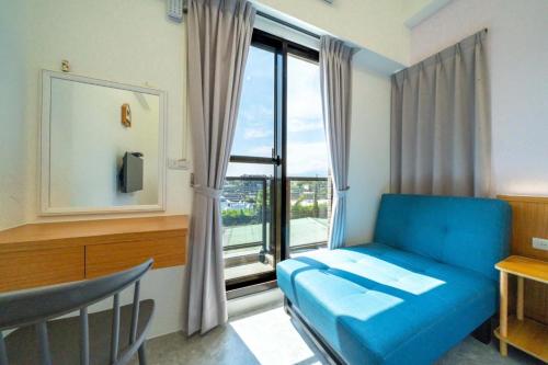 a room with a blue couch in front of a window at Aidao B&B in Dazhou