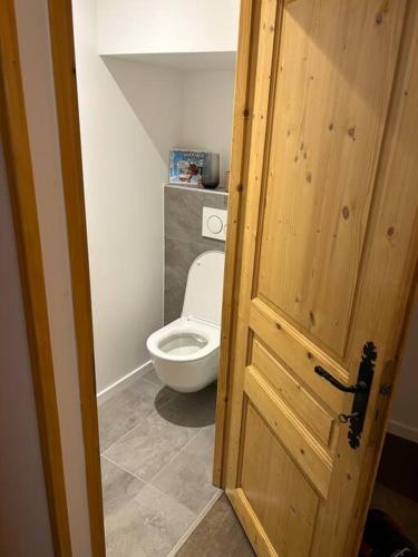 une salle de bain avec toilettes et porte en bois dans l'établissement L'Évasion Alpine - Superbe, calme et lumineux, à Vacheresse