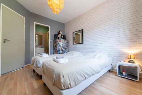 a bedroom with two beds and a brick wall at Le Cœur du Bouscat - Maison 3 Chambres à Bordeaux in Le Bouscat