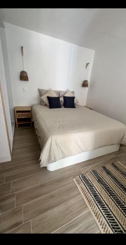 une chambre blanche avec un grand lit avec des oreillers bleus dans l'établissement Joli appartement T2 climatisé, au Barcarès