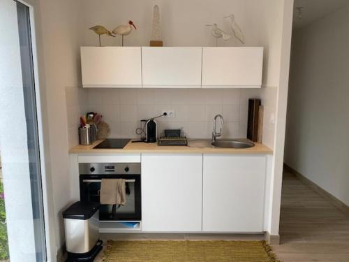 une petite cuisine avec des armoires blanches et un évier dans l'établissement La Maisonnette, à La Guérinière