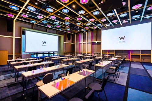 a dining room with tables and a projection screen at W Osaka in Osaka