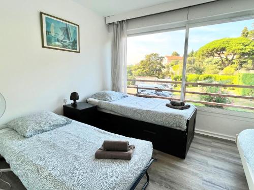 deux lits dans une chambre avec une grande fenêtre dans l'établissement Château de la mer, by Welcome to Cannes, à Cannes