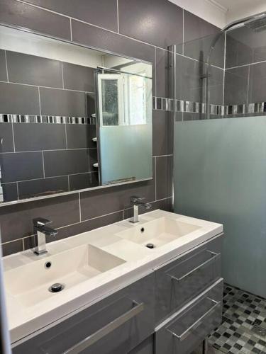 une salle de bain avec un lavabo blanc et un miroir dans l'établissement Villa avec piscine et Jacuzzi entre Aix et Marseille, à Gardanne
