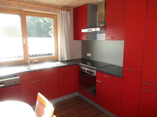 a red kitchen with a stove and a window at Naturparadies Silvia in Alberschwende