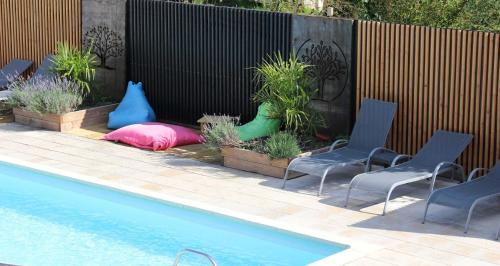 - une piscine avec deux chaises et un oreiller à côté d'une clôture dans l'établissement Gites les volets rouges d'Allonnes, à Allonnes