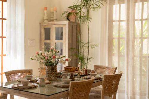 a dining room with a table with flowers on it at ELIVAAS 4 BHK with Pvt pool & Bar - PinkSky in Arpora