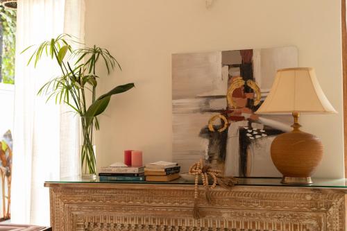 a table with a lamp and a painting on it at ELIVAAS 4 BHK with Pvt pool & Bar - PinkSky in Arpora