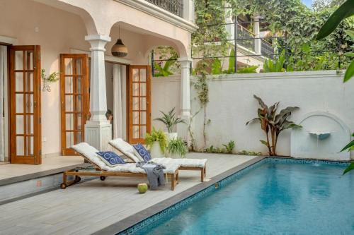 a house with a swimming pool and a patio at ELIVAAS 4 BHK with Pvt pool & Bar - PinkSky in Arpora