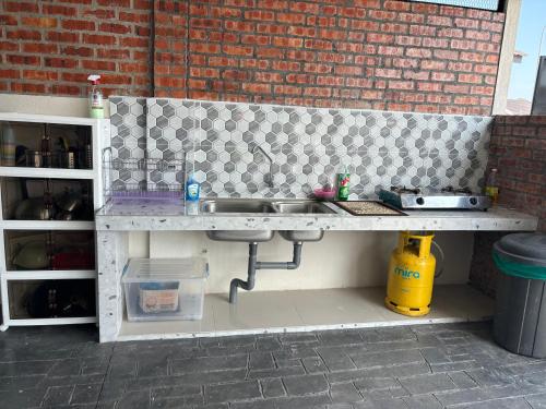 a kitchen with a sink and a brick wall at LaRinDa Teluk Kemang Private Pool - Islamic in Port Dickson