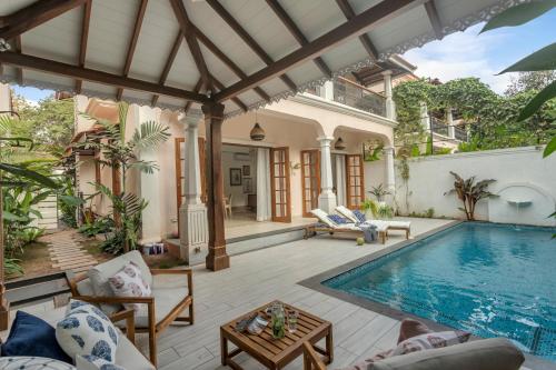 a house with a swimming pool and a patio at ELIVAAS 4 BHK with Pvt pool & Bar - PinkSky in Arpora