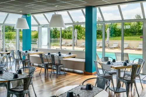 a restaurant with tables and chairs and a pool at Pey La Tour - Logis Hôtels & Restaurant in Salleboeuf