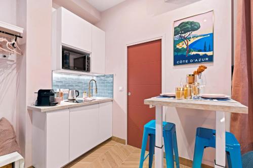 - une petite cuisine avec tabourets bleus et comptoir dans l'établissement Nice Renting - SPITALIERI - Chic & Cosy Art Deco Nest Nice Étoile, à Nice