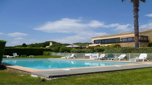 une piscine avec des chaises longues et un bâtiment dans l'établissement Un petit coin de paradis à Sanary sur mer, à Sanary-sur-Mer