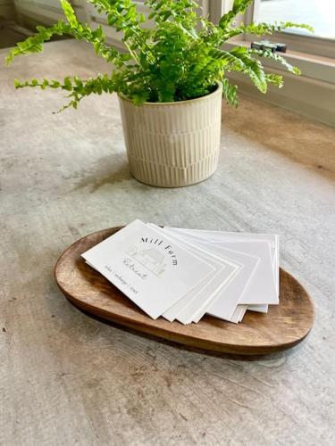 a wooden plate with a stack of papers on a table with a plant at Mill Farm Retreat in Gortin
