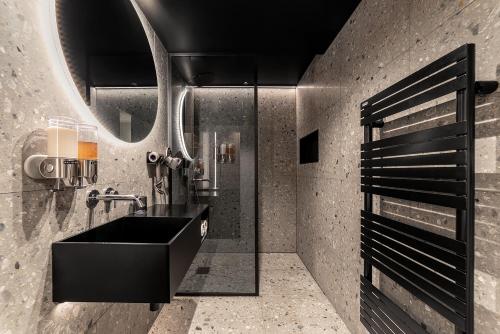 une salle de bain avec un lavabo noir et un miroir dans l'établissement Luxury Residence in old Marais, 3 BR, Patio, Sauna, Fitness Room, AC, à Paris