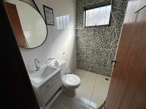 a bathroom with a toilet and a sink and a mirror at Casa de Temporada Olímpia 12 Pessoas in Olímpia