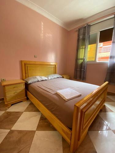 a bedroom with a wooden bed and a window at Appartement Mus saidia 1 in Saïdia