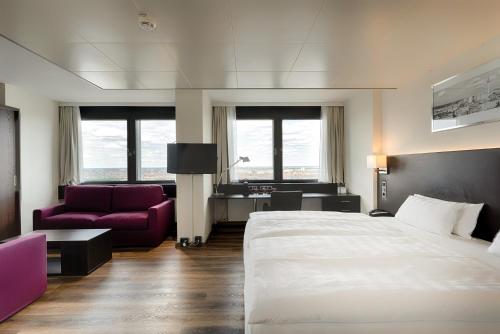 a hotel room with a large bed and a purple couch at Park Inn by Radisson Berlin Alexanderplatz in Berlin