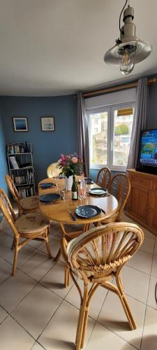 une salle à manger avec une table et des chaises en bois dans l'établissement Appartement La Plage Plouha, à Plouha