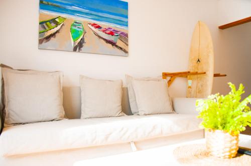 カレタ・デ・ファマラにあるAsana Surf House Famaraの白いソファと枕、そして壁にはサーフボード