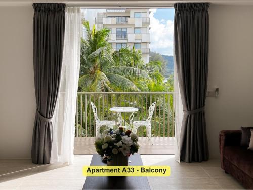 a living room with a balcony with a table and chairs at By the Sea- Pool and Sea View in Batu Ferringhi