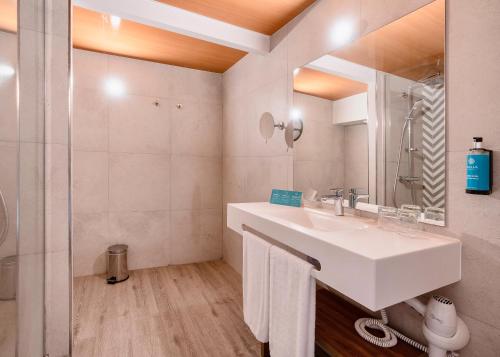 a white bathroom with a sink and a mirror at Alua Atlantico Golf - All Inclusive in San Miguel de Abona