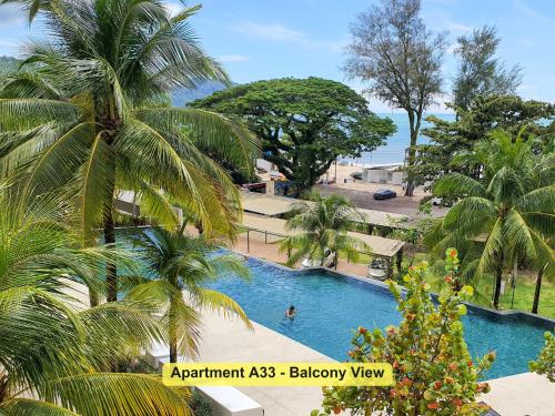 a swimming pool with palm trees in a resort at By the Sea- Pool and Sea View in Batu Ferringhi