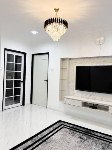 a living room with a flat screen tv and a chandelier at Rayyan Homestay in Pasir Puteh