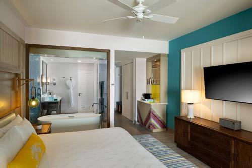 a bedroom with a bed and a tv and a bathroom at Margaritaville Island Reserve Riviera Maya - An Adults Only Karisma All-Inclusive Experience in Puerto Morelos