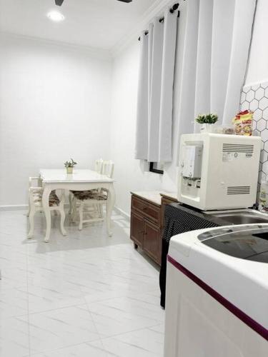 a white kitchen with a table and a microwave at Rayyan Homestay in Pasir Puteh