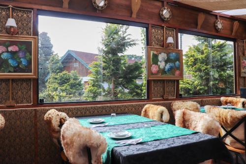 a dining room with a table and some windows at Pousada Campos do Jordao Suites in Campos do Jordão