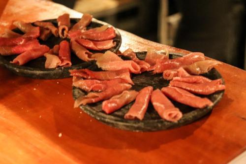 a person holding a bowl of bacon on a table at Pousada Campos do Jordao Suites in Campos do Jordão
